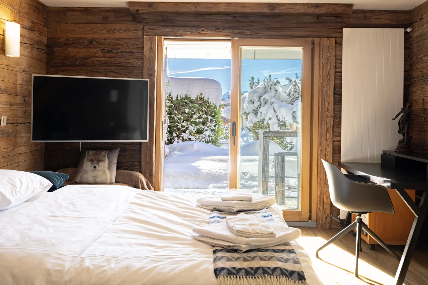 Chambre avec accès au balcon enneigé d'un chalet en gestion locative