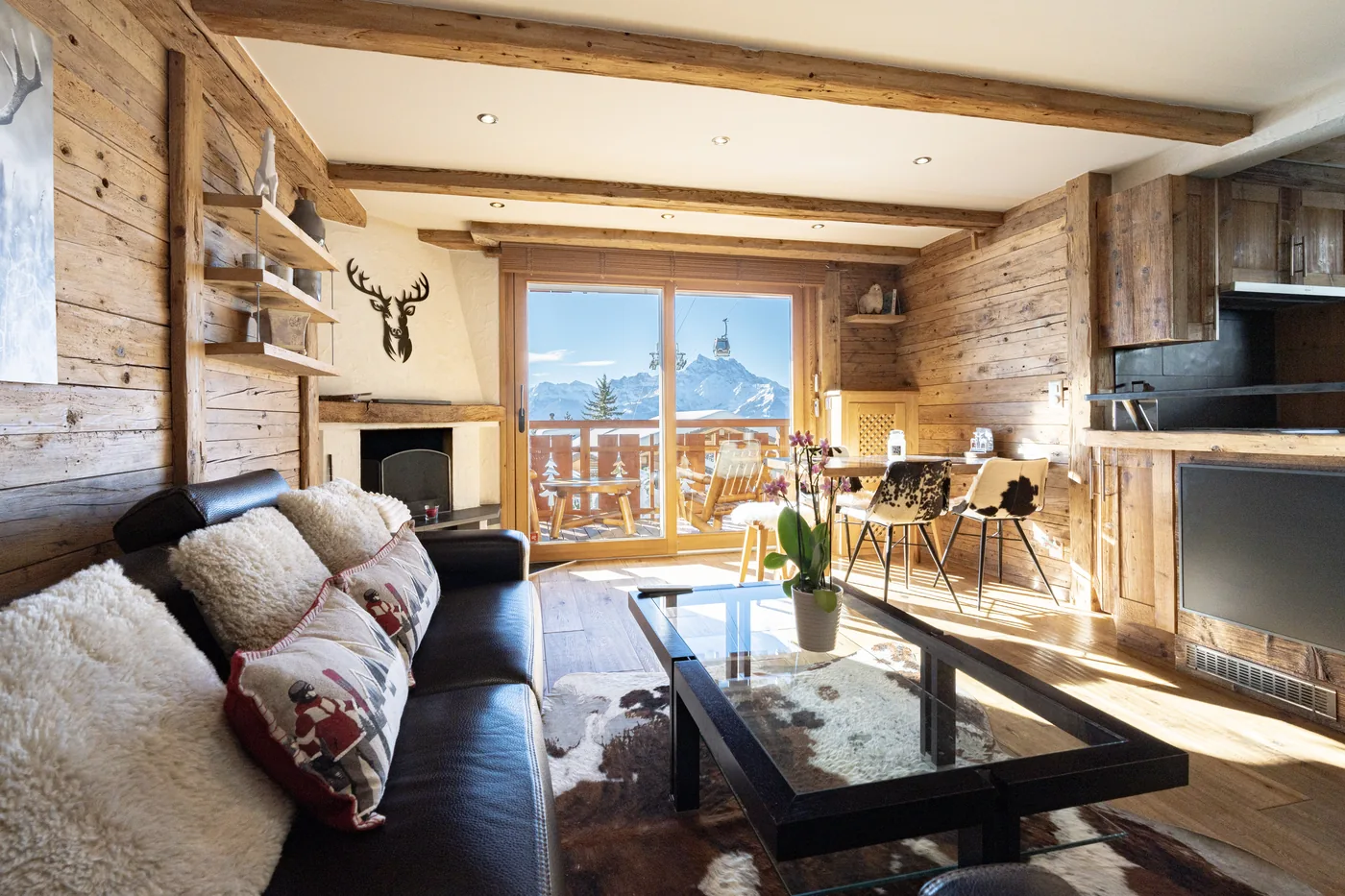 Salon en vieux bois avec cheminée et vue montagne d'un chalet en gestion locative