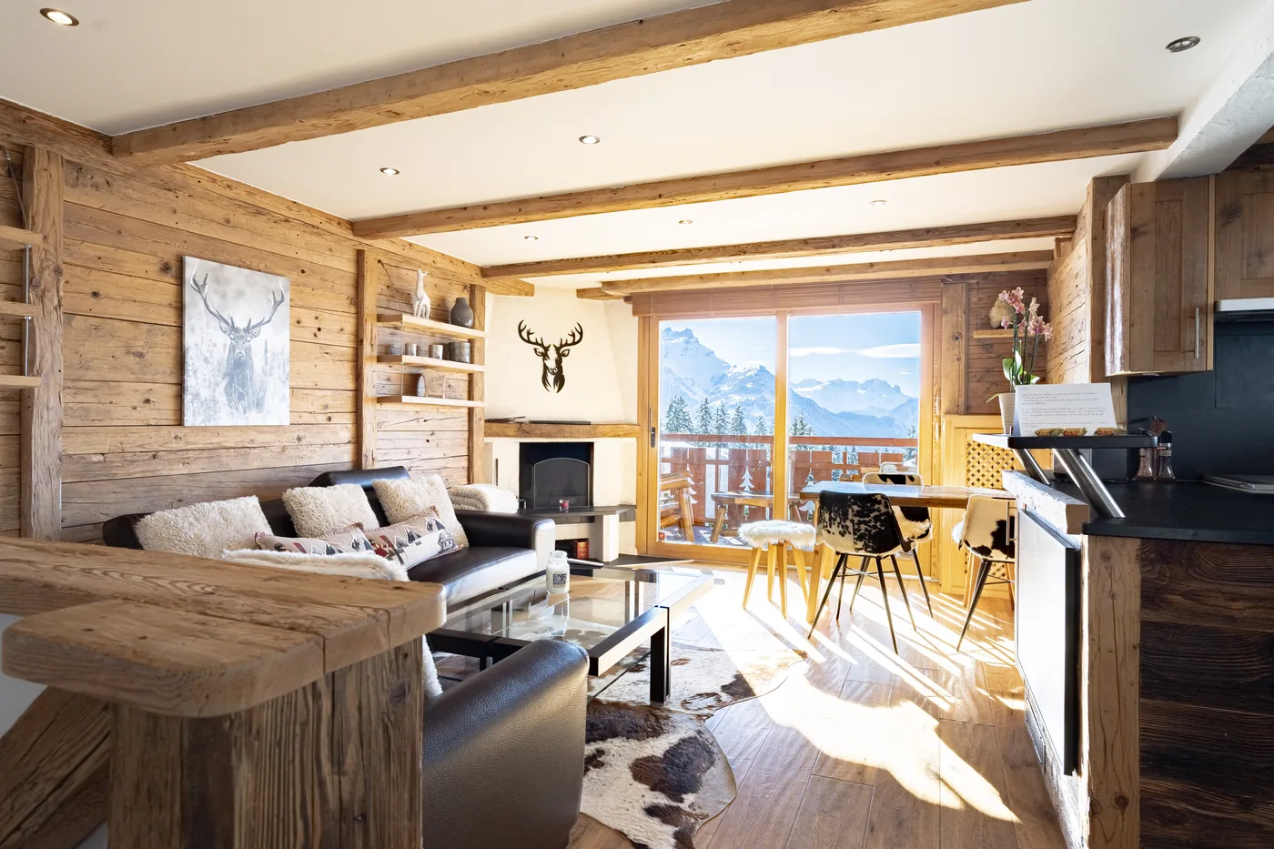 Salon de chalet en vieux bois avec cheminée et vue montagne, en gestion locative Séjours Alpin