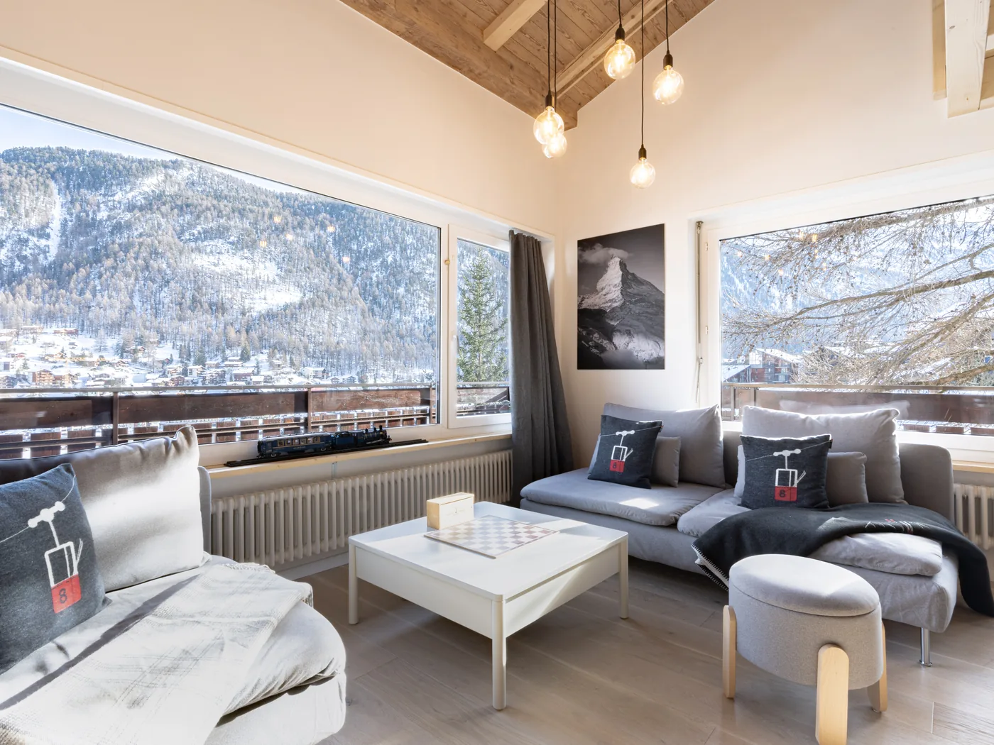 Salon d'un attique de luxe en gestion par Séjours Alpin, avec vue sur le village enneigé