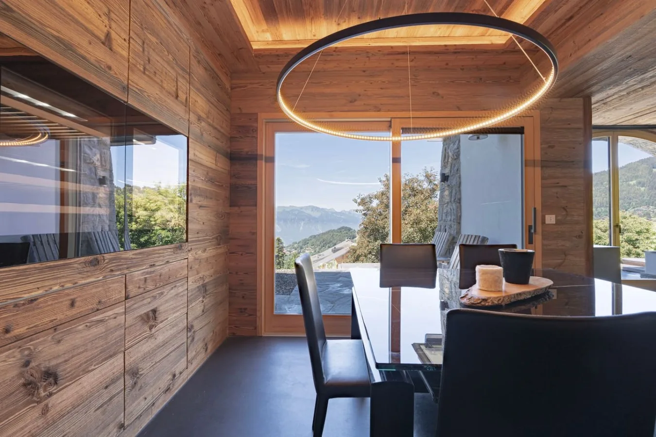Dining area under a circular pendant light, old-wood walls and ceiling, Villars-sur-Ollon