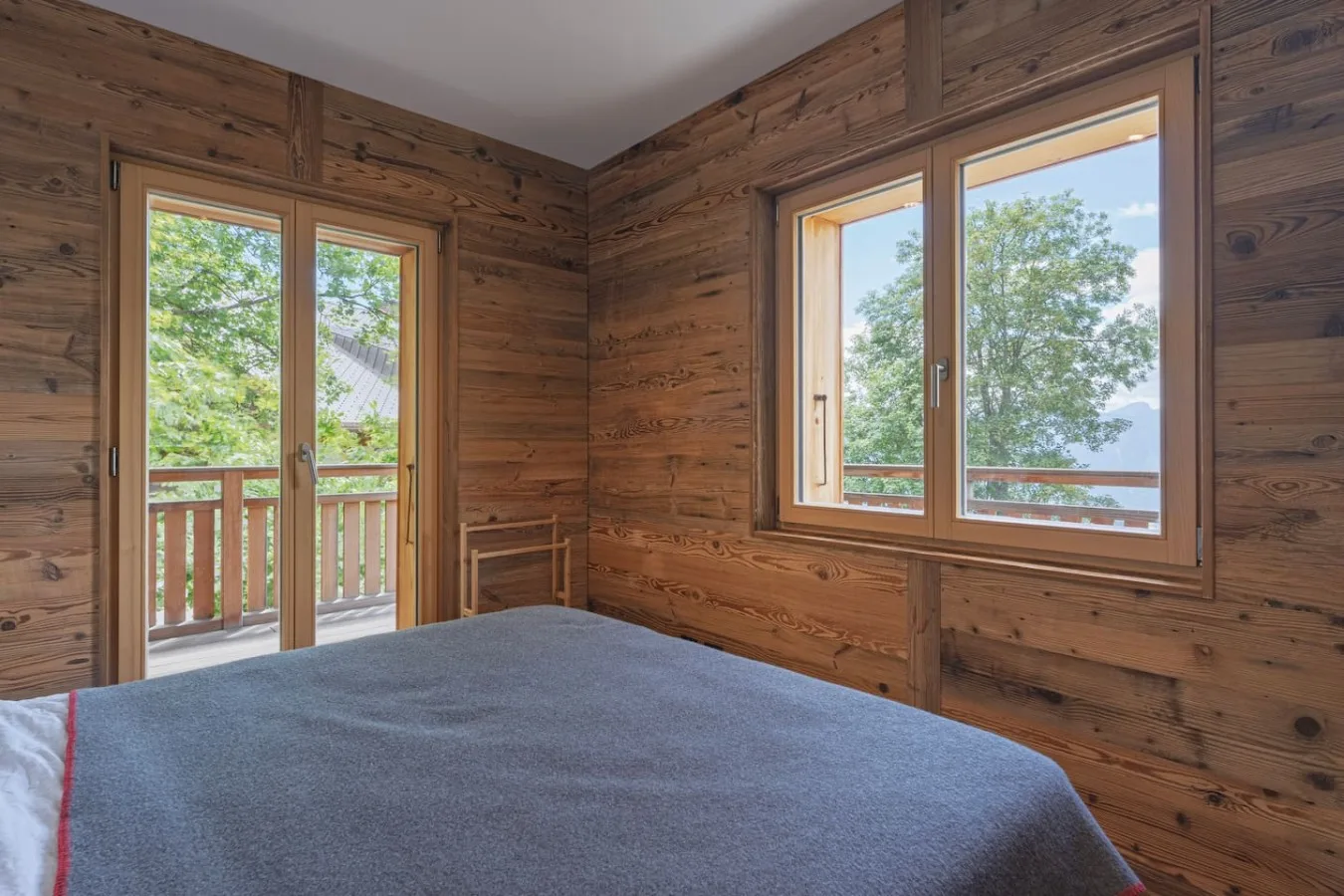 Old-wood bedroom with large bed and windows onto the trees, Villars