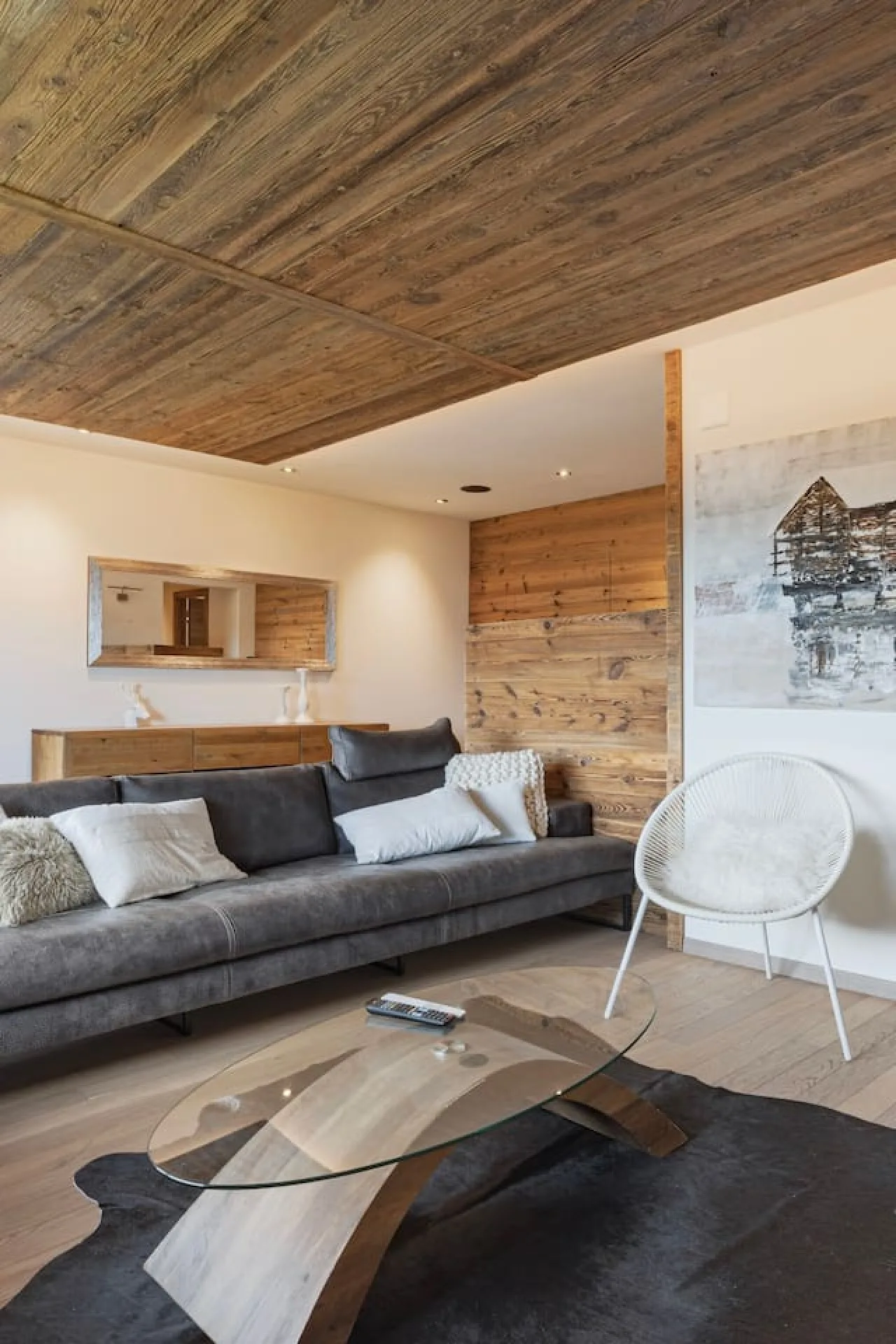 Living room with large television, stone wall and sofa, upscale apartment in Villars-sur-Ollon