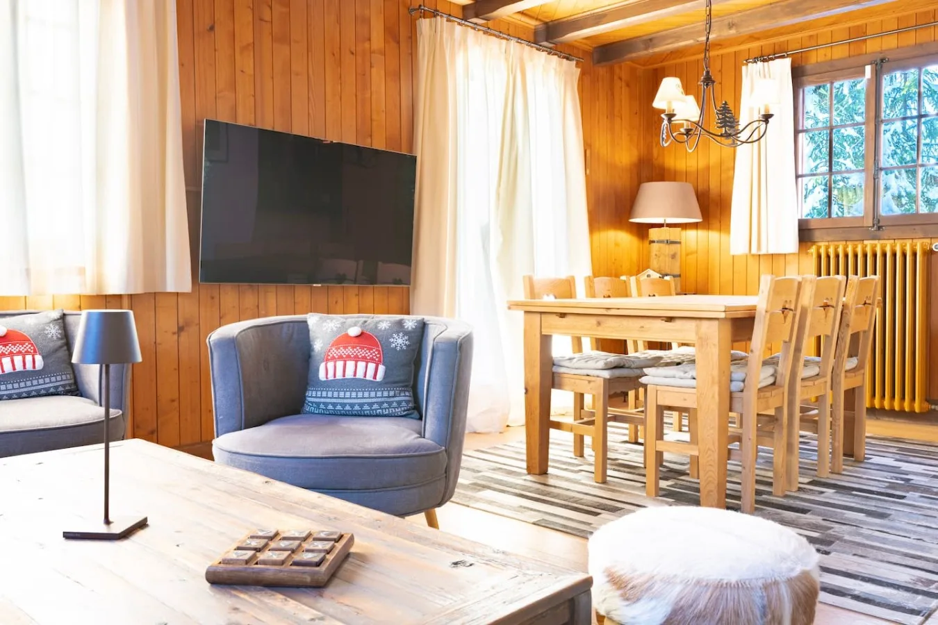 Wooden living room of the chalet with sofas, dining table and large windows, Villars