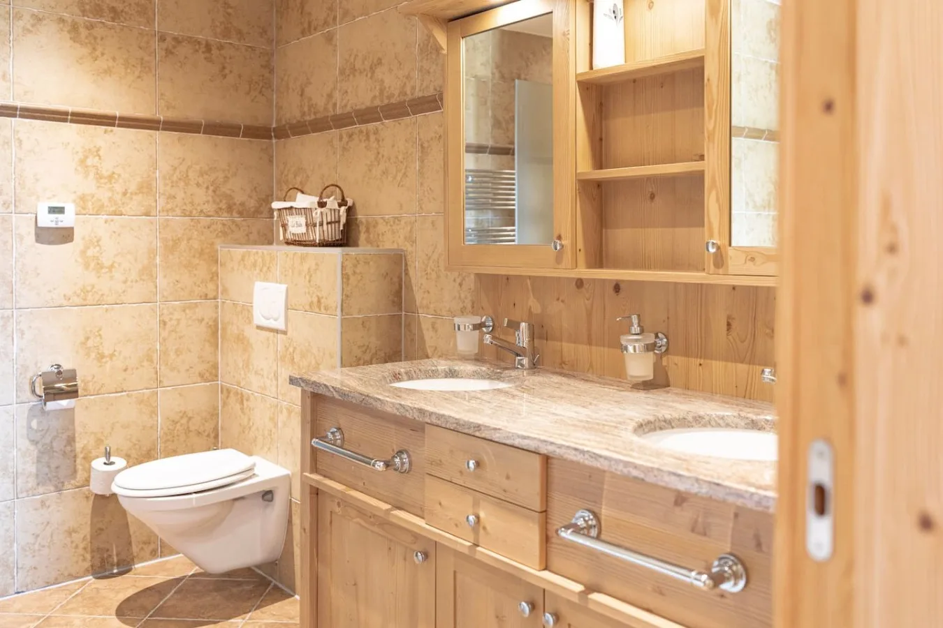 Light stone bathroom with double basin, apartment with sauna in Villars