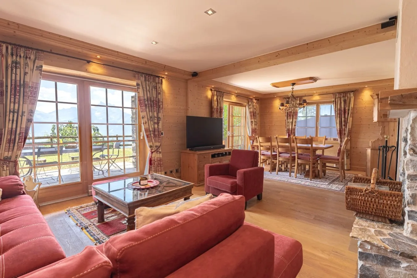 Large living room with red sofas, dining table and windows onto the garden, Villars-sur-Ollon