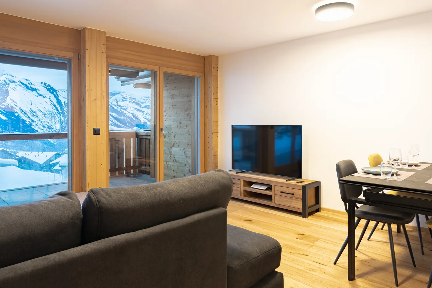 Salon avec baies vitrées et vue montagne — appartement en gestion locative à Ovronnaz