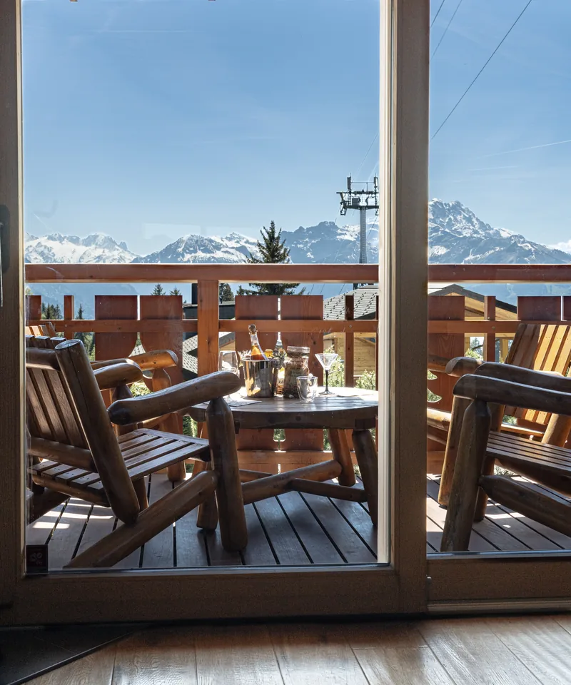 Balcon avec table en bois et vue montagne d'un chalet en gestion locative