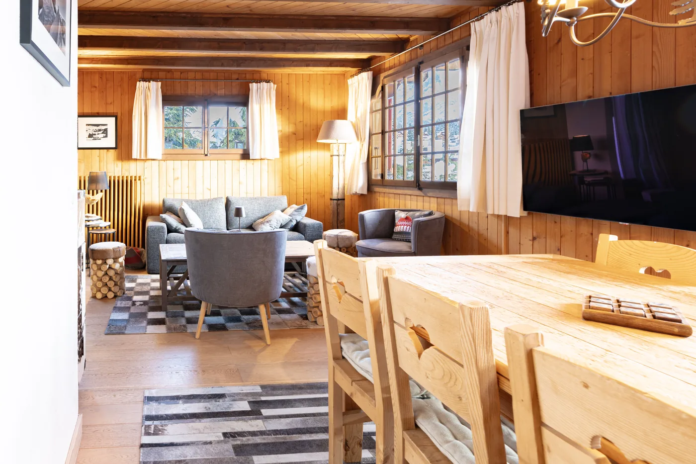 Séjour chaleureux avec TV et table à manger d'un logement en gestion locative Séjours Alpin