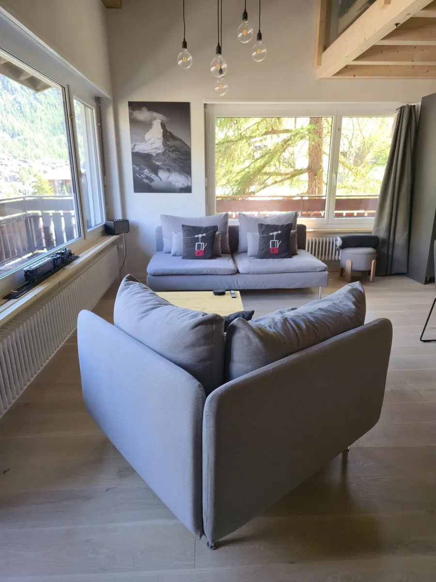 Salon avec grande baie vitrée et vue sur le village de Zermatt — appartement en gestion locative