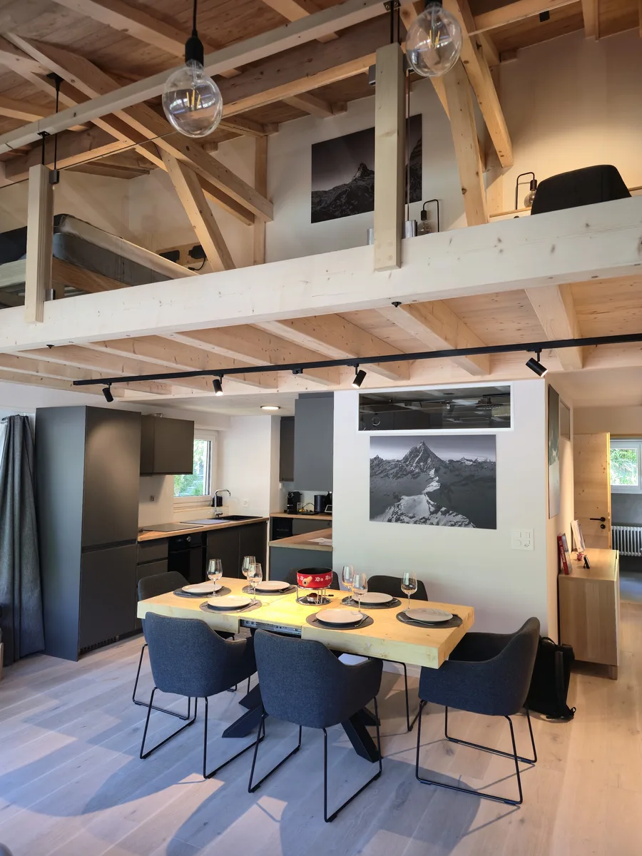 Séjour avec mezzanine et charpente en bois d'un appartement en location à Zermatt, géré par notre conciergerie