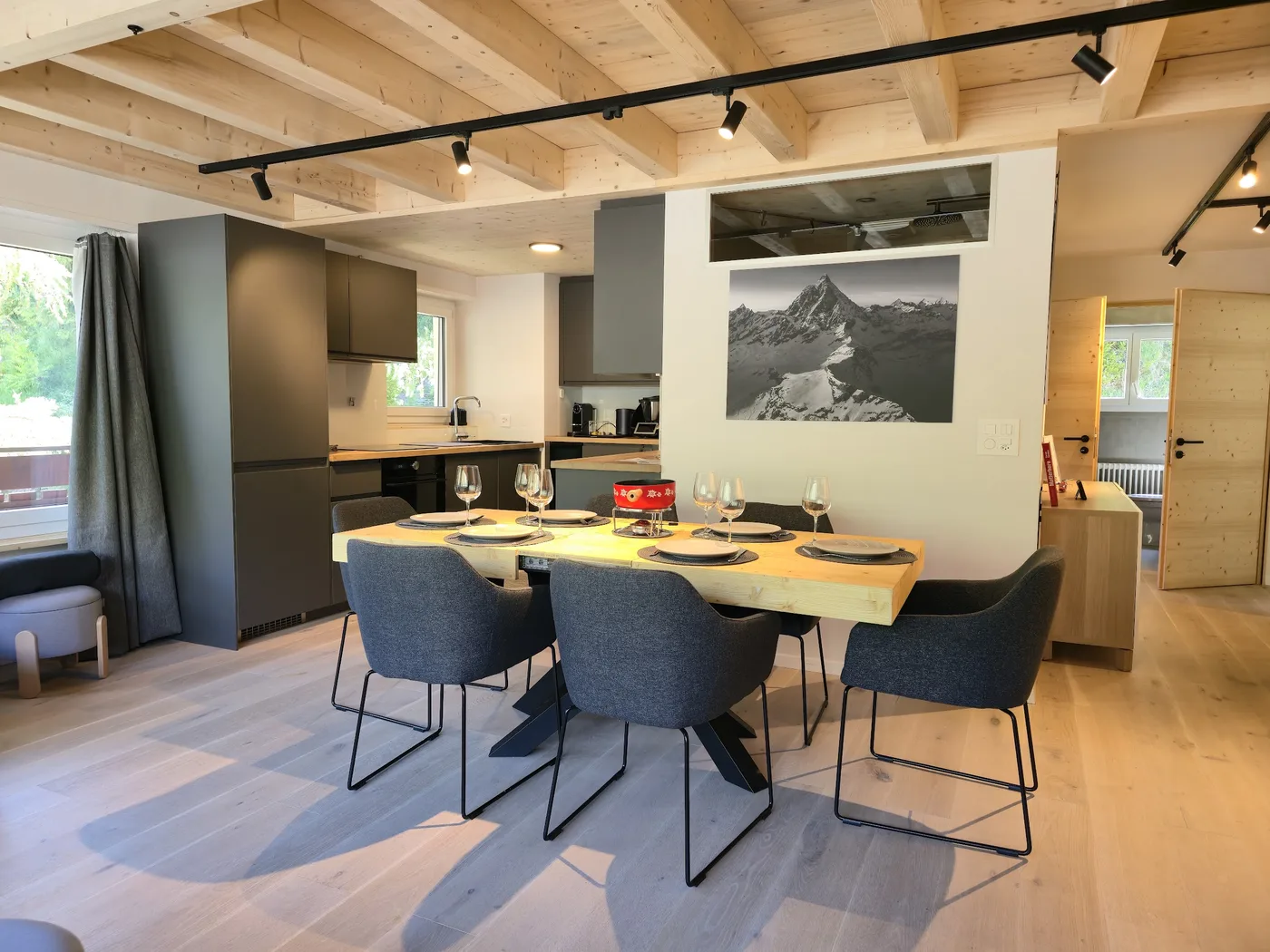 Séjour avec table dressée et cuisine ouverte d'un appartement en location courte durée à Zermatt