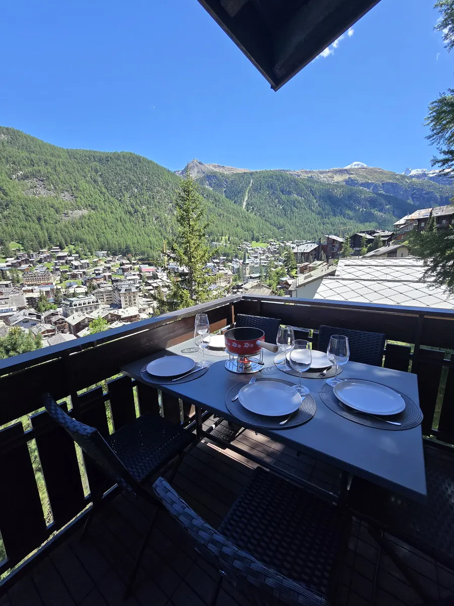 Terrasse avec table dressée et vue sur le village de Zermatt, appartement en gestion locative